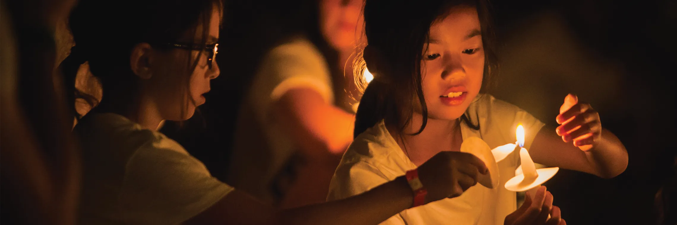 girls lighting candles for night meeting