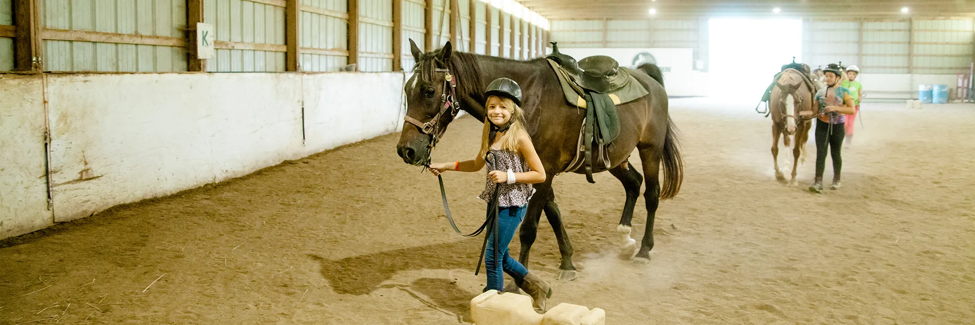 A girl walking with a horse at camp