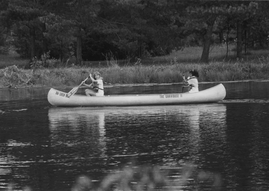 An old school photo of kids canoeing at camp